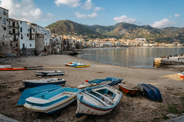Beautiful old harbor with wooden fishing boats,colorful waterfront stone houses and sandy beach in...