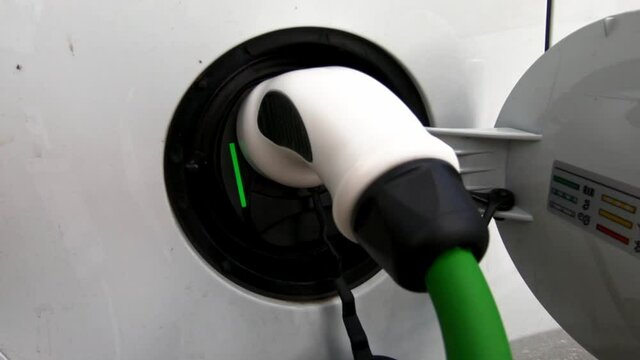 A closeup view of a white electric vehicle being charged in HD