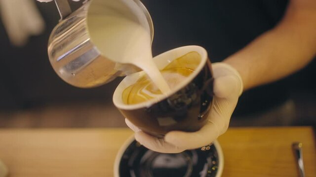 Barista hands drawing perfect milk foam picture in cup of fragrant cappuccino