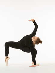 A girl in black clothes and Pointe shoes on a white isolated background performs dance and ballet poses and movements.