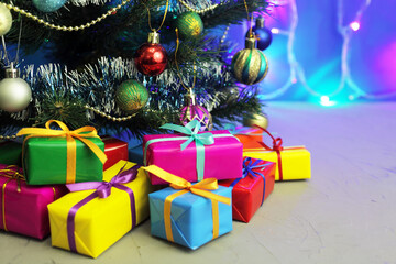New Year's gifts under a Christmas tree decorated with Christmas gifts and tinsel