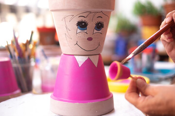 Art, creativity and people concept - close up of female artist painting a flower pot in studio
