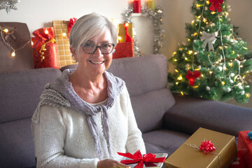 Obraz na płótnie Canvas Senior woman happy receives a new tablet as a Christmas present. One elderly modern people tech and social enjoying Christmas holidays