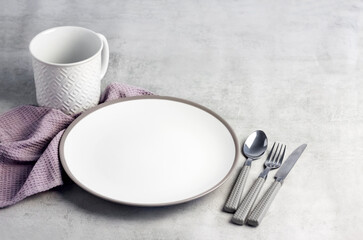 Table setting. White plate, mug, cutlery and napkin.
