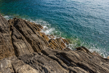 Close-up of cliffs and sea in front of the Riomaggiore village, Cinque Terre National Park in Liguria, La Spezia, Italy, Europe. UNESCO world heritage site. 