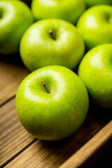 Freshly harvested green apples in the wooden crate. Selective focus.
