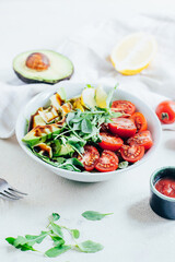 tomato salad arugula avocado lemon in white plate on light background