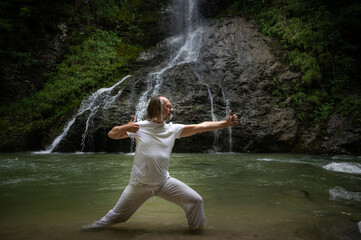 Bogenschützenposition des Yogalehrers vor Wasserfall