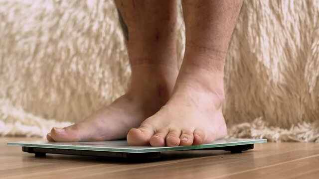 Feet of man stand on scales. Naked male legs stand on scales. Concept of controlling your weight