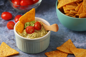 Homemade guacamole with corn chips and cherry tomatoes