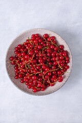 Fresh red currant in wooden bowl on grey table