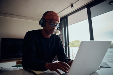 African American male working from home using laptop. Happy African American male working from home with headphones on. High quality photo 