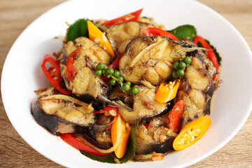Stir fried spicy cat fish in white dish on wooden table