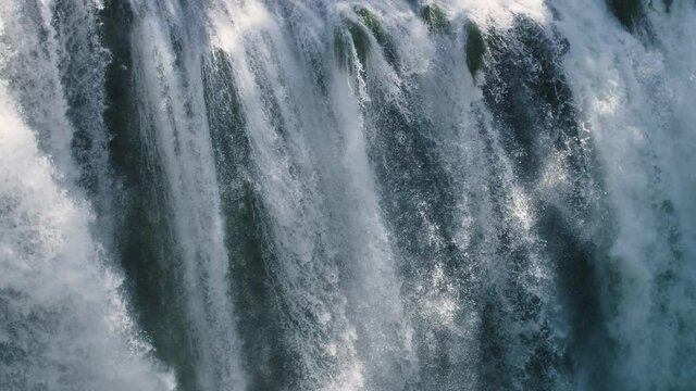 Beautiful close up of a big waterfall. Nature background with detailed texture. Fresh and clean river water flowing down a mountain environment. Powerful view of the natural landmark. Slow-motion, 4K.