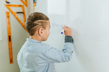 Elementary school student writing on the blackboard by felt-tip in the classroom