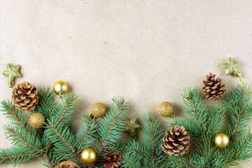 Border of fir tree branch with cones and gold decoratin on craft paper for christmas card with copy space for text.