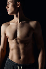 athlete with a naked torso looks to the side on a black background