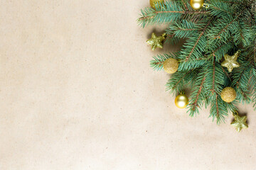 corner of fir tree branch with gold decoration on craft paper for christmas card with copy space for text.