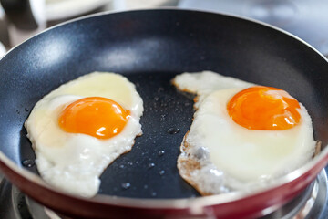 Breakfast getting ready. Sunny side fried eggs on the pan, closeup.