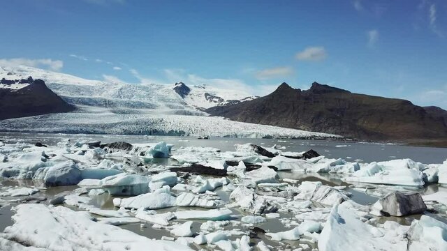 Aerial drone flight over Glacier Lagoon with icebergs.