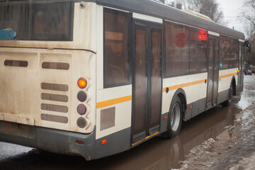 Bus in winter. Transport on the road travels through a puddle.
