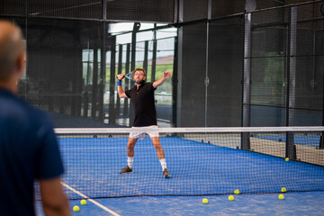 Monitor teaching padel class to man, his student - Trainer teaches boy how to play padel on indoor...