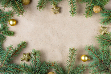 frame of fir tree branch with gold decoration on craft paper for christmas card with copy space for text.