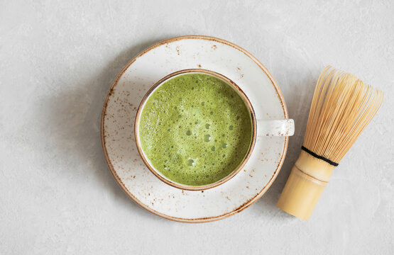 Matcha green tea. Homemade matcha latte and bamboo whisk on a gray concrete background closeup. Top view, flat lay.