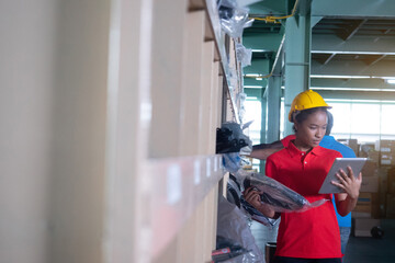 Warehouse worker using digital tablet checking goods and supplies on shelves in a large warehouse.