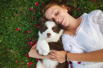 Young female owner in a grass with a cute border collie puppy