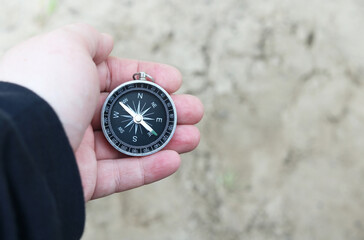 Old classic navigation compass in hand on natural background as symbol of tourism with compass,...