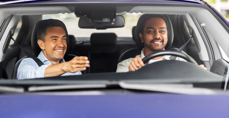 driver courses and people concept - happy smiling car driving school instructor teaching young man to drive