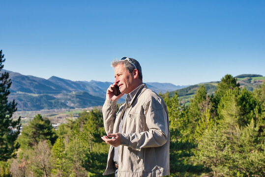 Homme d'affaires au t&eacute;l&eacute;phone en pleine nature qui est libre gr&acirc;ce &agrave; son business en ligne