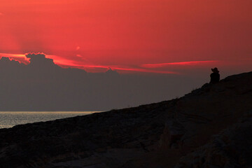 Silhouette of a woman watching sunset over distant horizon.