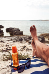 Man sunbathing on a rocky sea ocean beach.