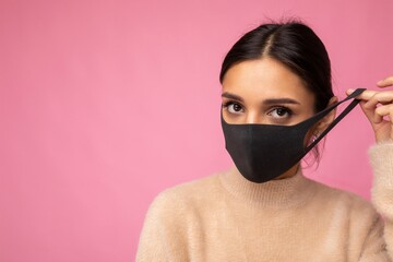 Photo of young attractive woman wearing handmade cotton fabric face mask isolated over colourful background wall. Protection against COVID-19