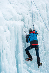 escalador subiendo por una cascada de hielo con la cuerda de seguridad