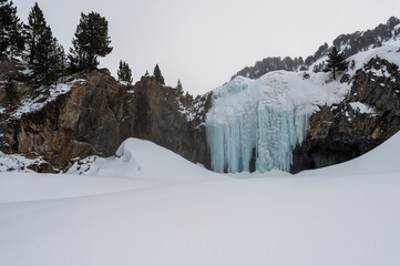 frozen waterfall between the snowy mountain walls