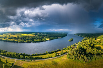 
Impressive storm clouds over the river Daugava in warm sunny day. Aerial view over colorful crop fields and pine forest.
