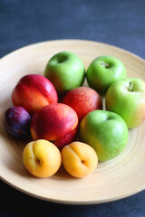 Wooden bowl with various colorful fruit. Selective focus.