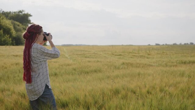 Girl stands in a wheat and take some photos of fields