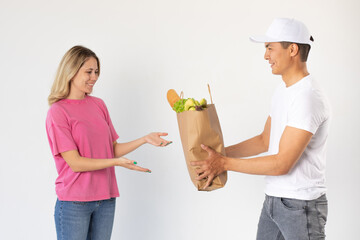 The delivery man gives the woman a bag of groceries.