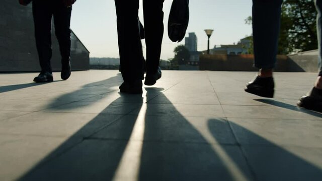 Low angle view of legs in formal trousers and shoes walking outdoors near business center while men and women are going to work. People and city concept.