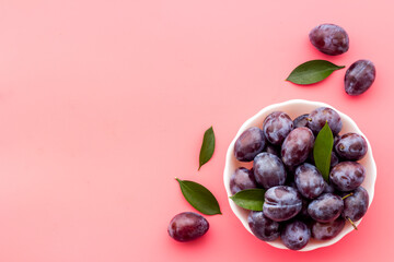 Ripe garden plums in bowl. Cherry fruit with leaves. Top view