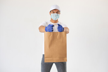 A delivery man in a protective mask and gloves holds a craft bag. Mock-up.