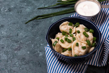 Traditional russian pelmeni or meat dumplings with sour cream