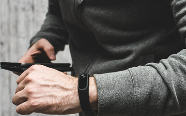 man checks data from fitness bracelet on his smartphone