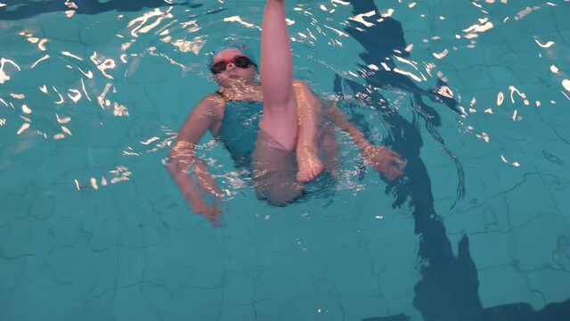The girl is on training in synchronized swimming.