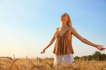 Obraz premium Woman in ripe wheat spikelets field on sunny day