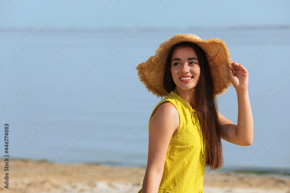 Canvas Prints Beautiful young woman wearing straw hat on beach. Stylish headdress